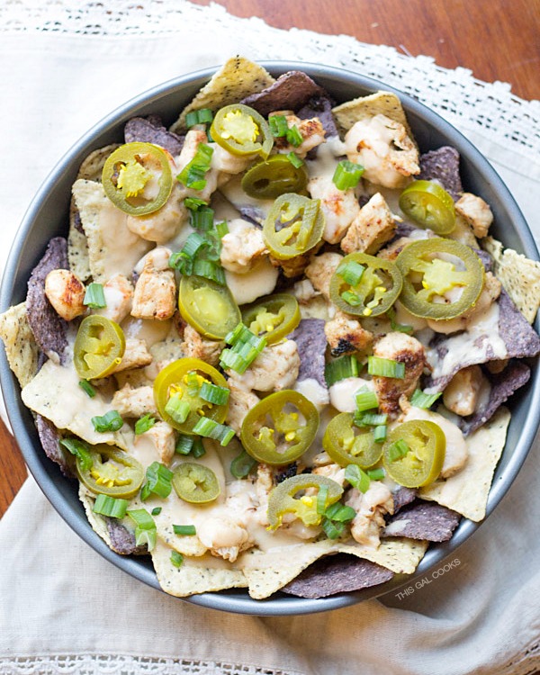 Cilantro Lime Chicken Nachos: lime and blue tortilla chips are topped with cilantro lime grilled chicken, homemade cheese sauce, jalapeños and green onions. Simple but crazy good.