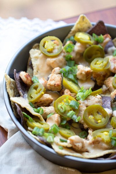 Cilantro Lime Chicken Nachos: lime and blue tortilla chips are topped with cilantro lime grilled chicken, homemade cheese sauce, jalapeños and green onions. Simple but crazy good.