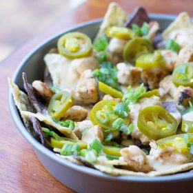 Cilantro Lime Chicken Nachos: lime and blue tortilla chips are topped with cilantro lime grilled chicken, homemade cheese sauce, jalapeños and green onions. Simple but crazy good.