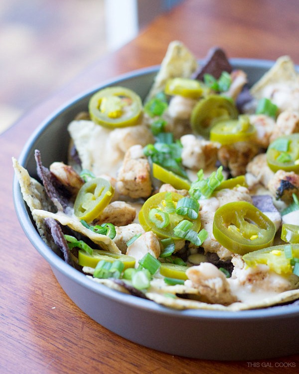 Cilantro Lime Chicken Nachos: lime and blue tortilla chips are topped with cilantro lime grilled chicken, homemade cheese sauce, jalapeños and green onions. Simple but crazy good. 