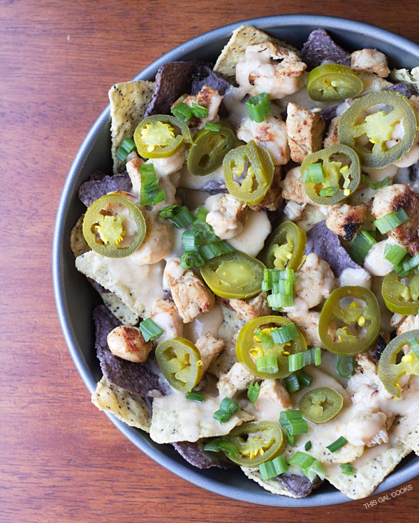 Cilantro Lime Chicken Nachos: lime and blue tortilla chips are topped with cilantro lime grilled chicken, homemade cheese sauce, jalapeños and green onions. Simple but crazy good.