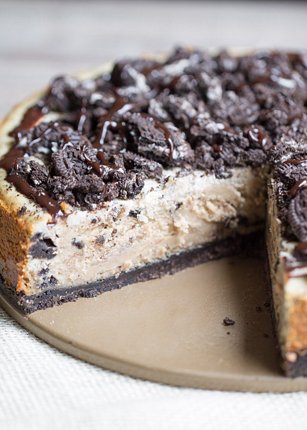 The BEST Peanut Butter Oreo Cheesecake. This creamy peanut butter cheesecake is filled and topped with Oreo cookies and drizzled with hot fudge! | This Gal Cooks