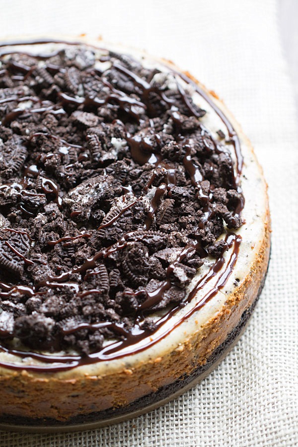 The BEST Peanut Butter Oreo Cheesecake. This creamy peanut butter cheesecake is filled and topped with Oreo cookies and drizzled with hot fudge! | This Gal Cooks