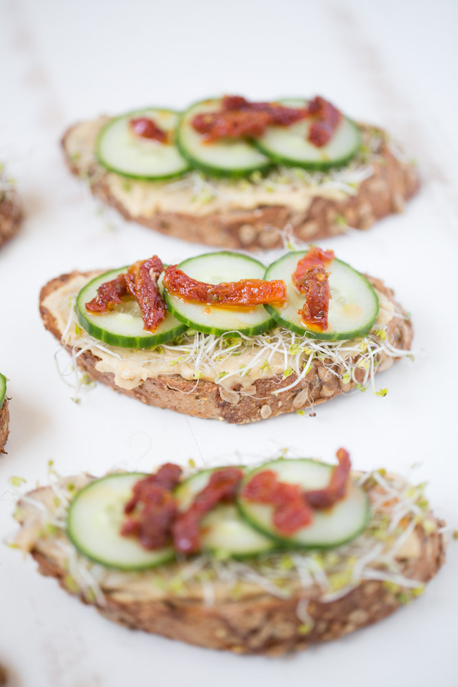 Roasted Garlic Hummus Toast with broccoli sprouts, cucumber and sundried tomatoes | This Gal Cooks